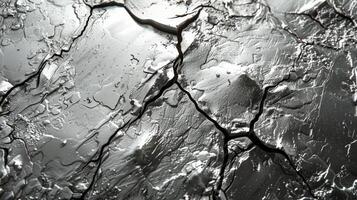 Close up view of a metallic surface featuring complex cracks and shimmering reflections caused by the presence of liquid. The details are enhanced by natural light. photo