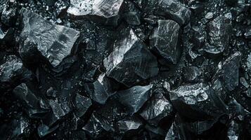 Shiny black coal pieces lie scattered, showcasing their uneven surfaces and sharp angles, catching low light and creating a dramatic visual contrast. photo