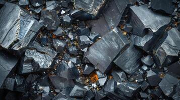 Shiny black obsidian stones are densely scattered across a rocky surface, showcasing various shapes and textures under natural light, with some warm reflections illuminating the scene. photo