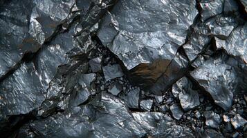 A detailed view of shiny black rocks interspersed with fine gravel showcases the intricate textures and patterns in a natural environment during daylight. photo