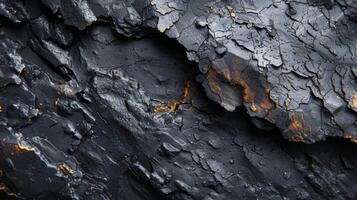 Close up view of a rock surface displaying remarkable textures, dark tones, and striking orange highlights interwoven with deep cracks, revealing its geological complexity. photo