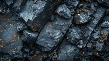 Coal fragments lie on the ground, displaying a variety of sizes and textures. The surface reflects light, revealing deep black and hints of golden colors. photo