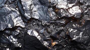 A close up view reveals a striking pattern of dark, reflective rocks with sharp edges and intricate textures under bright light, highlighting their unique geological features. photo