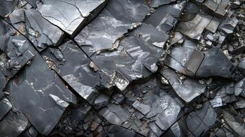 The rugged surface displays angular pieces of black volcanic rock, with distinct layers and a glossy finish, illustrating the geological evolution of the area. photo
