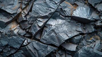 Broken pieces of gray slate rock create a textured surface, highlighting the angular shapes and diverse shades of gray. The natural mineral patterns add visual interest and depth. photo