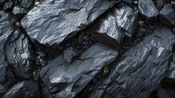 Close up view of dark slate rocks scattered on the ground at a coastal location, showcasing their shiny surfaces under soft, diffused light during cloudy weather. photo