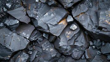 The close up view reveals dark mineral formations that exhibit sharp edges and cracked surfaces, highlighting the natural beauty and complexity of the geological landscape in a mining area. photo