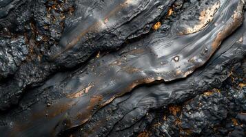 Complex textures show smooth dark surfaces with metallic gold highlights, that create an abstract design evoking natural elements such as lava flow or liquid metal photo