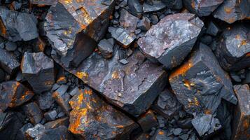 Rocks of various shapes and sizes are closely packed, displaying a mix of dark hues and striking orange oxidation. The geological features highlight their natural beauty and texture variations. photo
