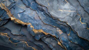 Textured surface of dark blue stone features striking gold veins creating an eye catching pattern, illuminated softly for a dramatic effect. photo