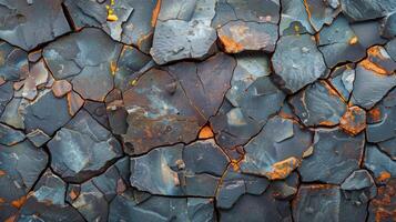 Close up view of cracked slate rock displaying distinctive blue gray tones and vibrant orange mineral deposits, showcasing the beauty of natural geological formations in daylight. photo