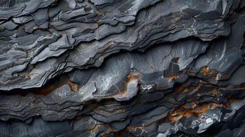 Intricate dark rock formations display unique textures and layered patterns, showcasing natural beauty through varying shades of gray and hints of rust, inviting exploration and study. photo