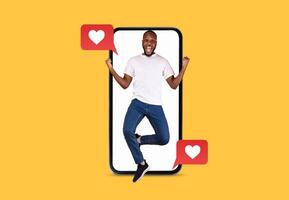 A joyful man is depicted leaping in excitement while interacting with a smartphone. Heart icons symbolize love, showcasing the joy of connecting through technology, perfect for Valentine's Day. photo