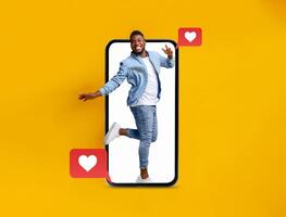 A person happily poses while emerging from a smartphone, symbolizing digital connections and love on Valentine's Day. Heart icons represent social media interactions and messaging. photo