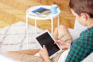 Teenager holding digital tablet with empty screen, home interior, top view, copy space photo