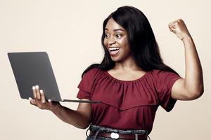 Emotional young african american woman holding her brand new modern laptop and gesturing, trading online, studio background, copy space. Computer, notebook, laptop, gadgets, modern technologies photo