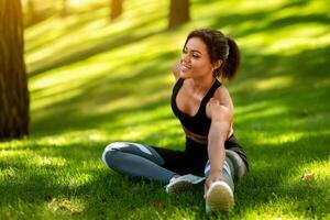 Healthy african woman warming up on the grass before jogging by park, free space photo
