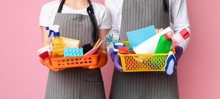 Baskets with cleaning supplies and tools in hands of unrecognizable couple standing on pink background, cropped image, panorana with free space photo