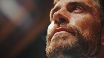 A man with a well groomed beard focuses intensely while exercising in a gym. The lighting highlights his features, capturing a moment of mental dedication and physical effort. photo