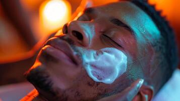 A man enjoys a facial treatment at a spa, his skin covered with a gentle cleansing foam. The warm, ambient light creates a calming atmosphere. photo