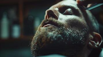 A man is reclining in a barbershop chair while a barber carefully shapes his beard with precision tools. Soft lights create a cozy atmosphere. photo