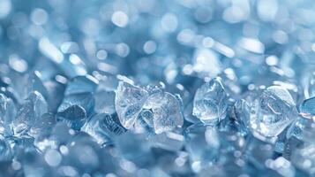 Shimmering blue glass fragments are scattered across a surface, reflecting light and creating a textured pattern. The close up view highlights the intricate details and clarity of the pieces. photo
