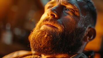 A man with a well groomed beard gazes upward, lost in thought, as soft golden light illuminates his face, highlighting the intensity of his expression. photo