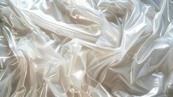 A transparent plastic sheet is spread out with visible wrinkles, reflecting soft light and creating an artistic atmosphere, suggesting a project in a creative workspace. photo