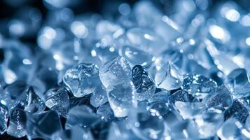 Various small glass like crystals are scattered closely together, sparkling in soft light. Their clarity and shape create a visually appealing texture in a tranquil setting. photo
