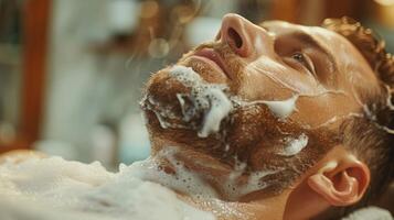 A man reclines in a barber chair with shaving cream lathered on his face and beard, enjoying a relaxing grooming session at a barber shop filled with warm afternoon light. photo