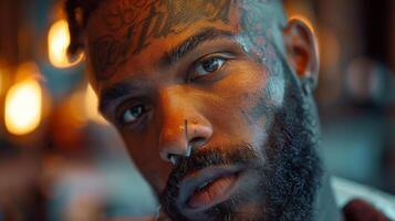 Man with striking facial tattoos and a captivating expression gazes directly at the viewer, illuminated by ambient light in a stylish urban environment. photo
