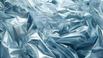 Blue plastic sheets are crumpled together, displaying a glossy surface with fascinating light reflections. The texture highlights the interplay of shadows and creases, creating depth. photo