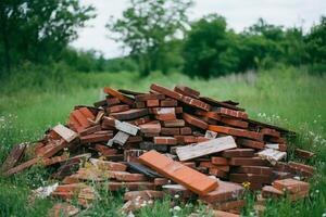 A pile of bricks in a grassy area surrounded by trees. photo