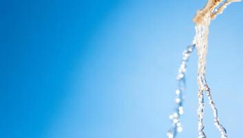 Water flowing against a clear blue sky, creating a refreshing scene. photo