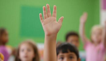 A child's raised hand in a classroom setting, indicating participation. photo
