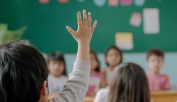 A child raising their hand in a classroom setting to answer a question. photo
