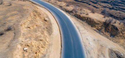 Aerial view of a winding road through a dry, rugged landscape. photo
