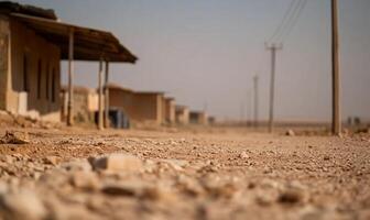 A dusty road lined with simple structures in a barren landscape. photo