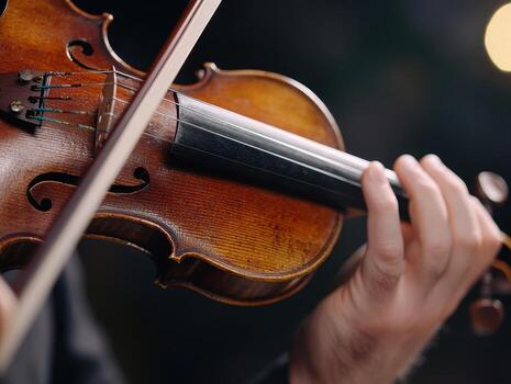Close-up of a Musician Playing a Violin with Focus on Strings and Bow in a Dimly Lit Setting photo
