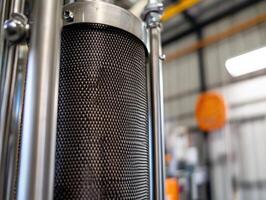A close-up of a metallic filter mesh, showcasing the intricate design and structure, set against an industrial background. photo