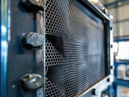 A close-up of a metal structure featuring a hexagonal mesh design, likely part of industrial machinery or a heat exchanger. photo