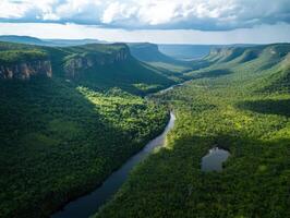 Aerial view of a lush green valley with a winding river, surrounded by mountains under a partly cloudy sky. photo