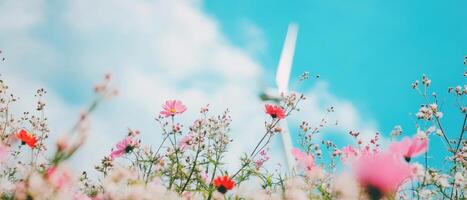 A vibrant field of colorful flowers under a bright blue sky, featuring soft clouds and a hint of a wind turbine in the background, evoking a serene atmosphere. photo