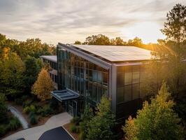 Modern building surrounded by trees, featuring solar panels and bathed in warm sunset light. photo