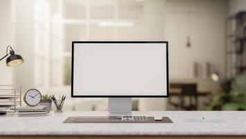 A computer with a white screen mockup and decorative items on a white desk set in a modern office. photo