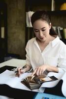 A confident Asian female architect boss works on a building's interior design at her desk. photo
