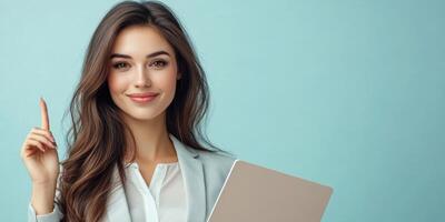 Young professional woman smiles confidently while holding a laptop and pointing her finger in a bright office setting photo