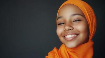 A Young Girl Smiles Wearing An Orange Headscarf photo