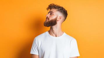 Young Man With Beard Looking Up Against Yellow Background photo