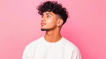 Young Man with Curly Hair Looking Upward Against Pink Background photo